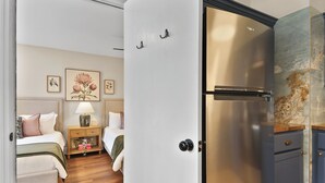 A bedroom with a bed, bedside table, lamp, and framed floral artwork on the wall. - New Meets Nostalgic- Cottage Sleeps 8 (Savannah)
