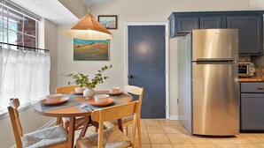 A kitchen with a stainless steel refrigerator, wooden dining table, and chairs. - New Meets Nostalgic- Cottage Sleeps 8 (Savannah)