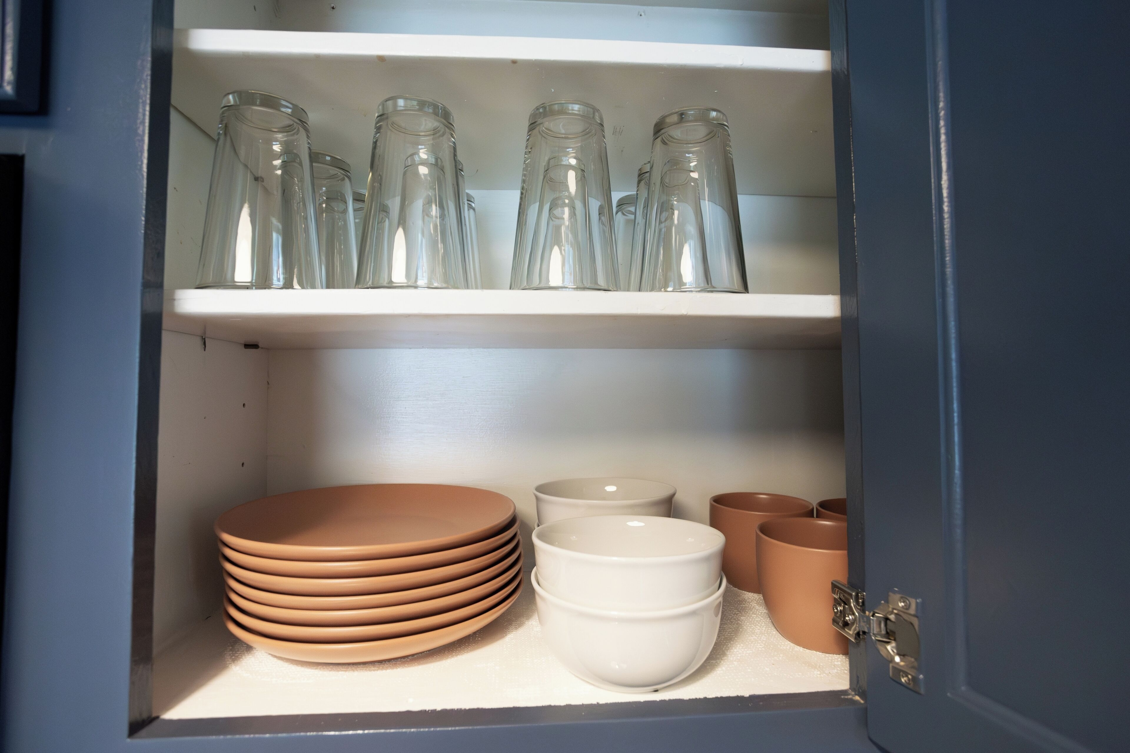 A cabinet with shelves containing glassware and ceramic dishes.