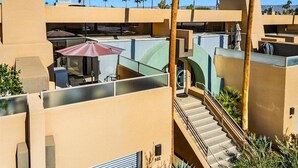 Ein modernes Hotel mit Dachterrasse, Palmen und einer Treppe zu den oberen Etagen.