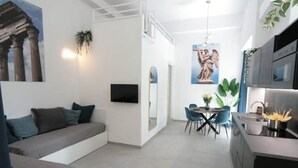 Una sala moderna con sofá, un comedor con mesa y sillas, y una cocina con fregadero y estufa.
