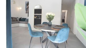 Un comedor con una mesa redonda, sillas azules y un jarrón con flores.