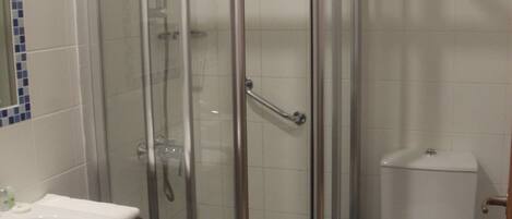A bathroom with a glass-enclosed shower, a white sink, and a toilet.