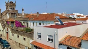 A street view with buildings, including a tower with a clock, and a shop with a sign. - Hotel Vila Verde (Castro Verde)