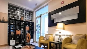 A modern living room with a black coffee table, yellow armchairs, and a black bookshelf. - Hotel Vila Verde (Castro Verde)