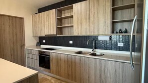 A modern kitchen with wooden cabinets, a black backsplash, stainless steel appliances, and a double sink.