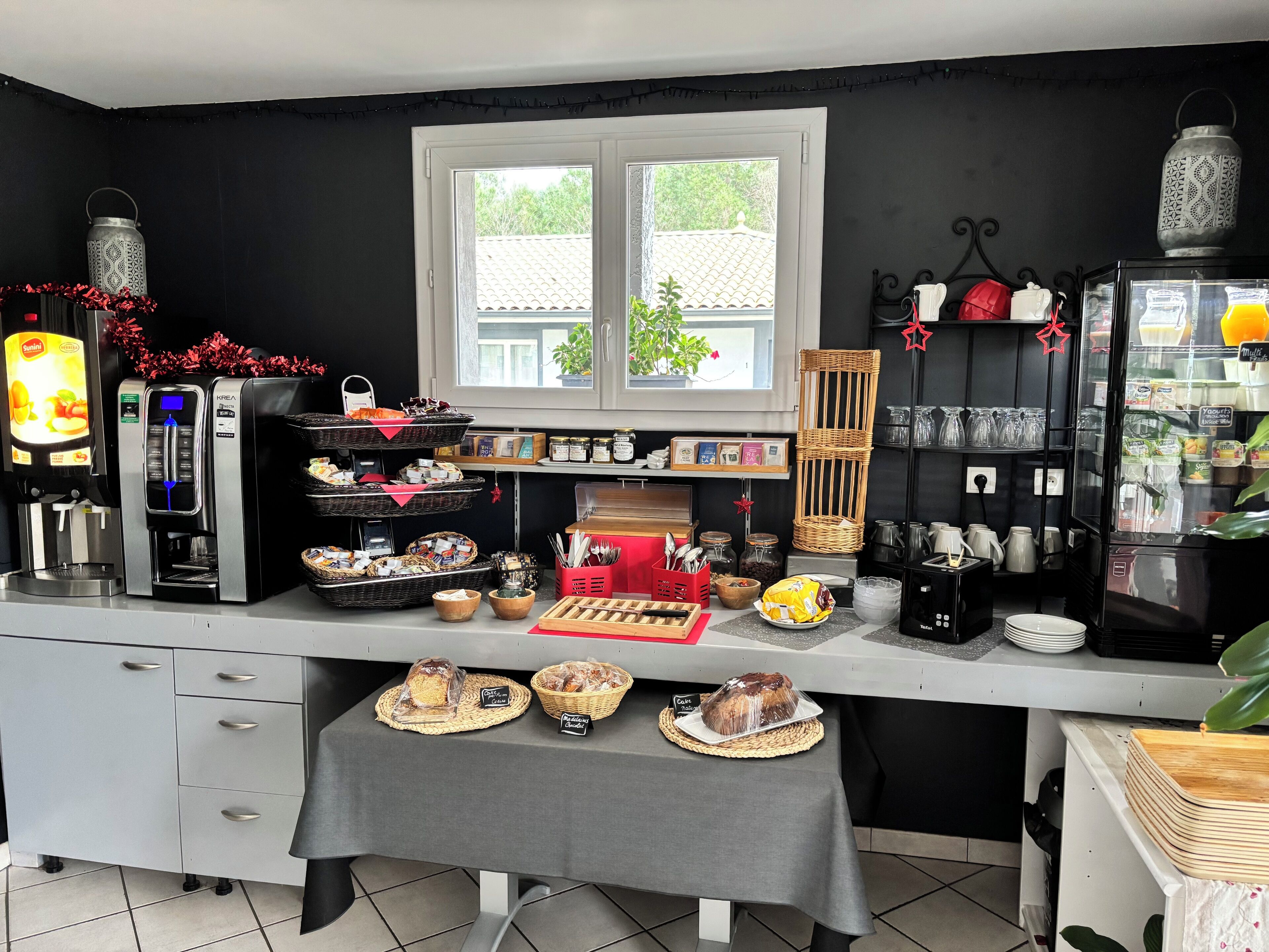 A kitchen area with a coffee machine, a refrigerator, and various food items displayed on the counter.