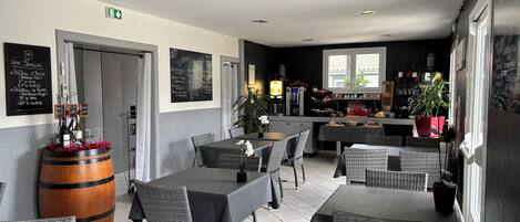 A restaurant interior with tables, chairs, a bar area, and a chalkboard menu.