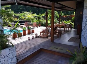 Un espace extérieur abrité comprenant une piscine, une terrasse en bois et divers aménagements pour s’asseoir.