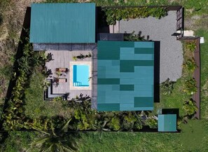 A modern house with a swimming pool, a covered patio, and a large garden area.