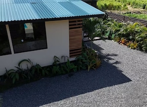 Un bâtiment moderne doté d’un toit en pente, entouré de gravier et de différentes plantes.