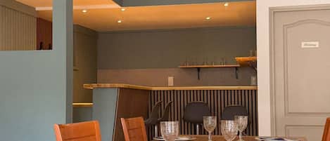 A dining area with a wooden table, chairs, and a mountain landscape painting above.