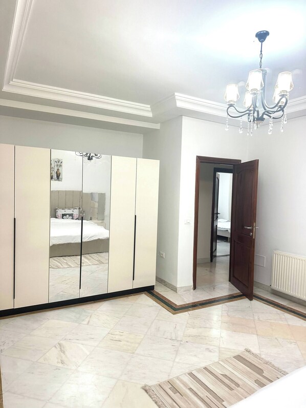 A bedroom with a large wardrobe, a bed, a chandelier, and a door leading to another room. - Luxury Stay With Panoramic Sea Views, Tourist Zone (Sousse)