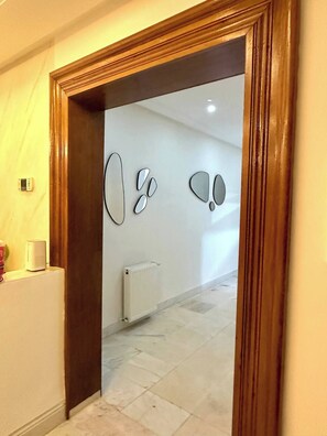 A hallway with a wooden door frame, a white radiator, and a wall-mounted intercom. - Luxury Stay With Panoramic Sea Views, Tourist Zone (Sousse)