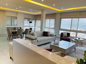 A modern living room with a sofa, coffee table, and dining area. - Luxury Stay With Panoramic Sea Views, Tourist Zone (Sousse)