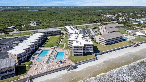 Een hotel aan de kust met meerdere gebouwen, een zwembad en een strand.