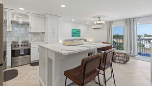 A modern kitchen with a central island, stainless steel appliances, and a view to the outside.