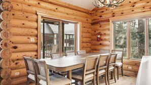 A log cabin interior with a dining table and chairs, large windows, and a chandelier. - Ridgeview Retreat, 5-bedroom cabin in Brian Head with jacuzzi, views and stocked (Brian Head)