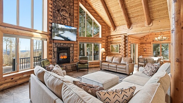 A log cabin interior with a stone fireplace, large windows, and a cozy seating area. - Ridgeview Retreat, 5-bedroom cabin in Brian Head with jacuzzi, views and stocked (Brian Head)