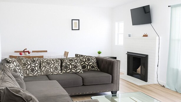 Una sala de estar moderna con un sofá modular, una mesa de centro de vidrio, una chimenea y un televisor montado.