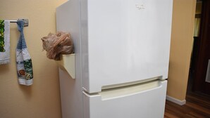 Et hvidt Whirlpool køleskab i et køkken med beige vægge og trægulv.