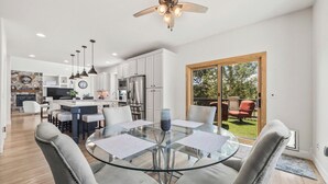A modern kitchen with white cabinets, a central island, and a dining area with a glass table and chairs.