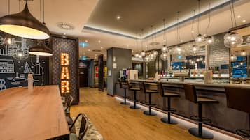 Un espace bar moderne avec un plancher en bois, des tabourets de bar, des luminaires suspendus et une fresque représentant un paysage urbain.