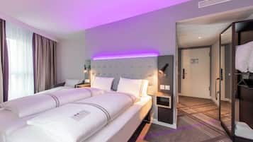 A hotel room with a large bed, bedside tables, a wardrobe, and a bathroom visible through an open door.