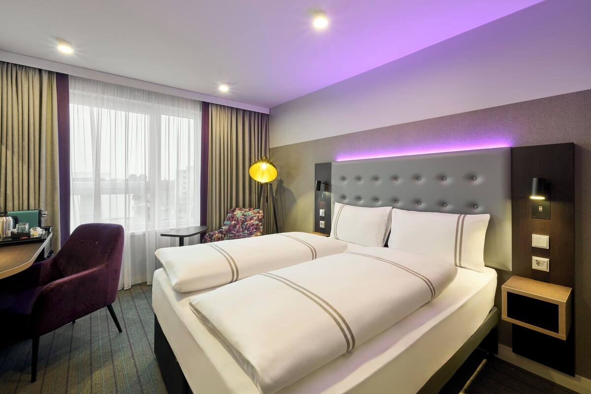 A hotel room with a large bed, a desk, a chair, and a small table.