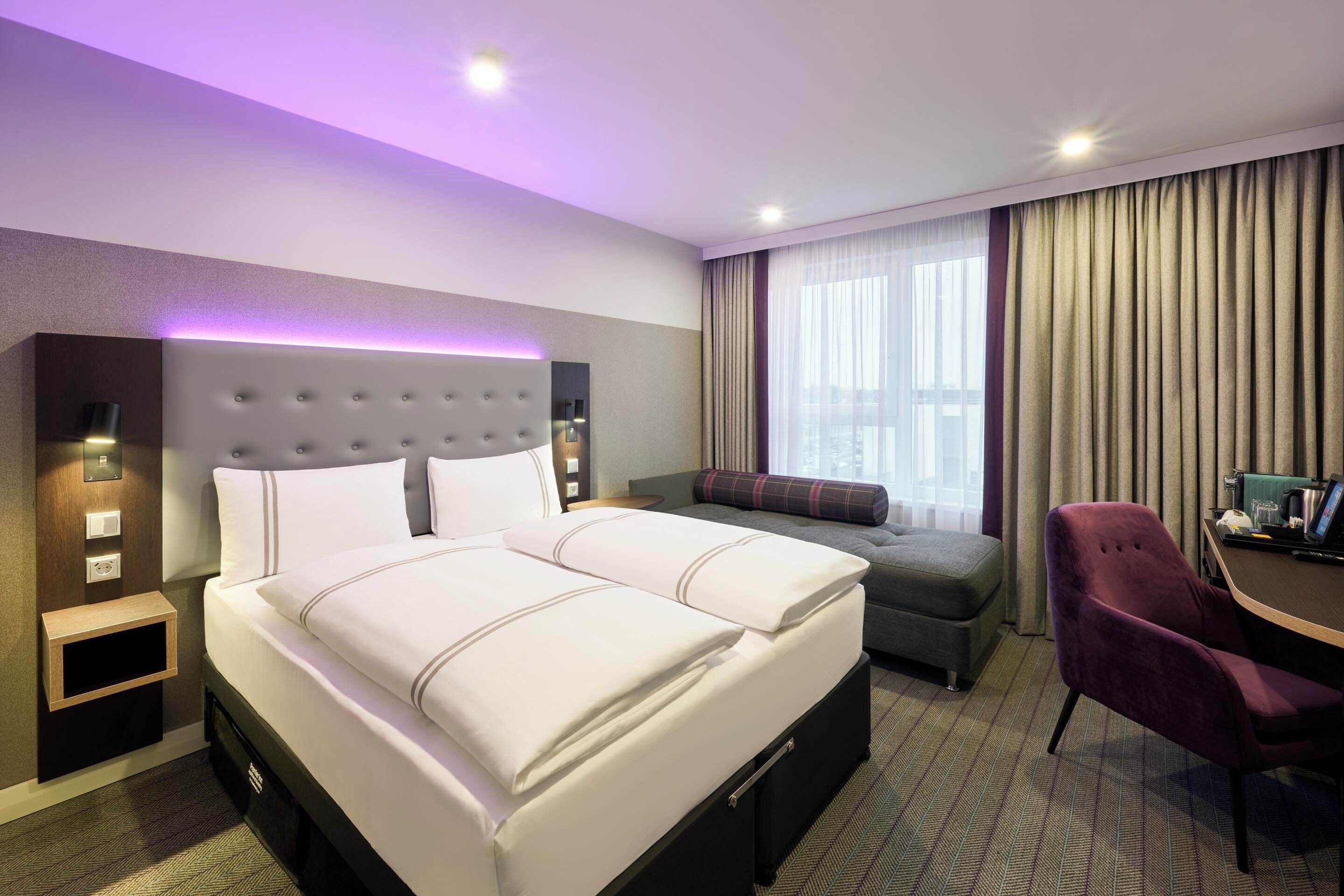 A hotel room with a large bed, a sofa, a desk, and a chair.