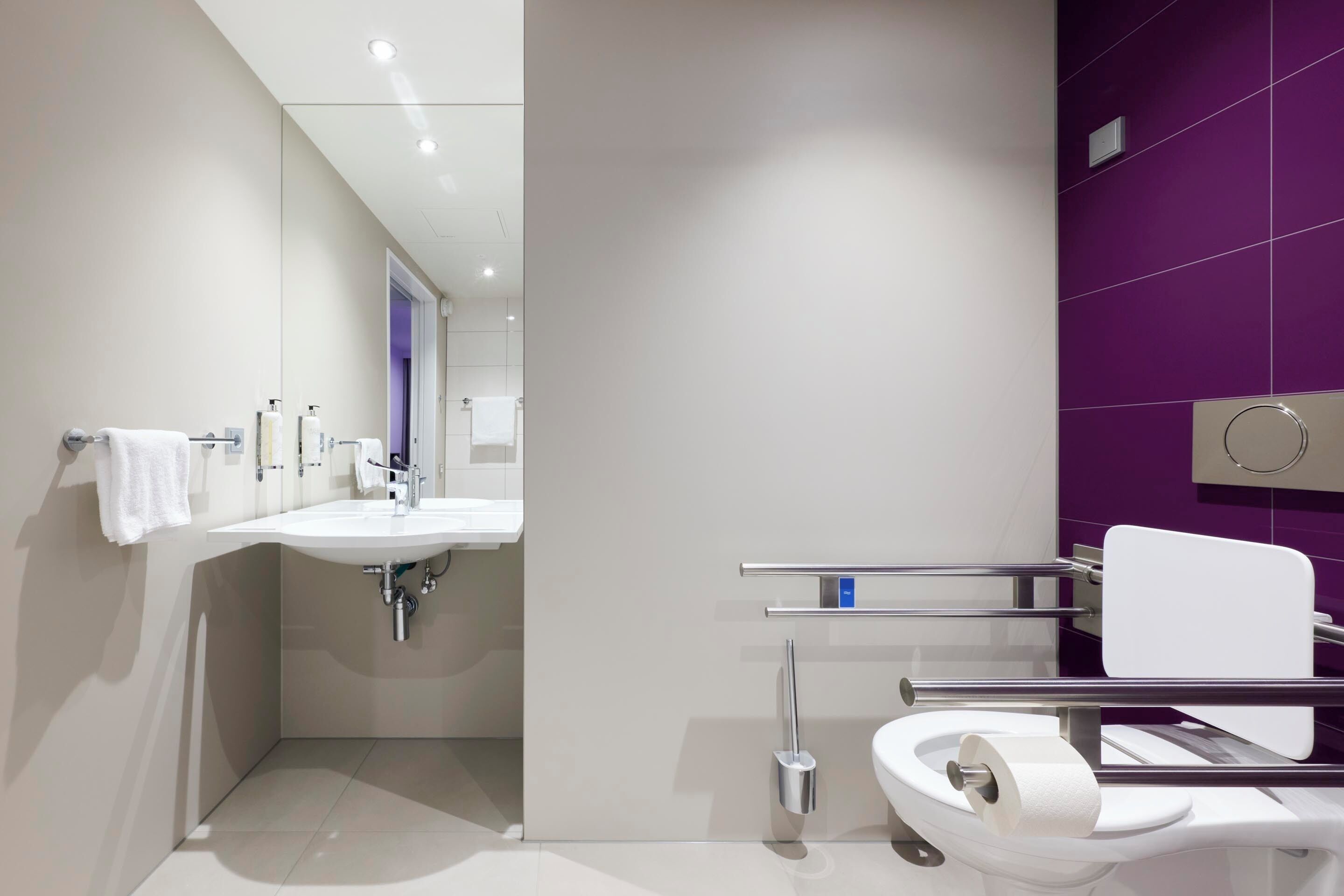 A modern bathroom with a white sink, a toilet, and a mirror.