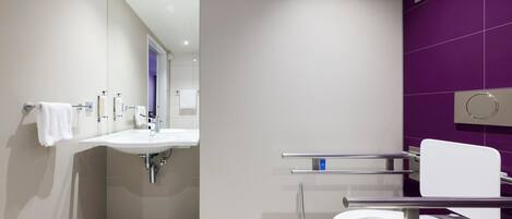 A modern bathroom with a white sink, a toilet, and a mirror.
