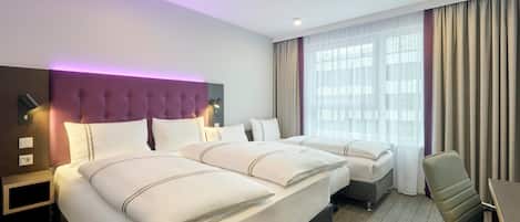 A hotel room with two beds, a desk, and a chair.