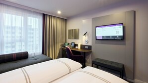 A hotel room with two beds, a desk with a computer, a chair, a TV mounted on the wall, and a window with curtains. - Premier Inn Stuttgart Zuffenhausen (Stuttgart)