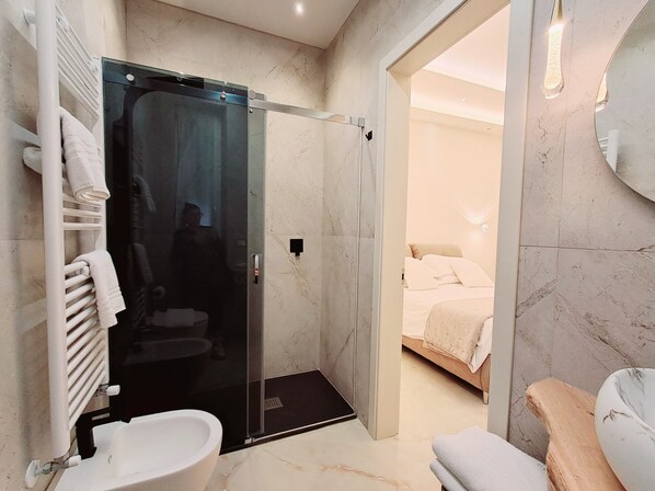 Un baño moderno con mampara de vidrio, lavamanos blanco y retrete.