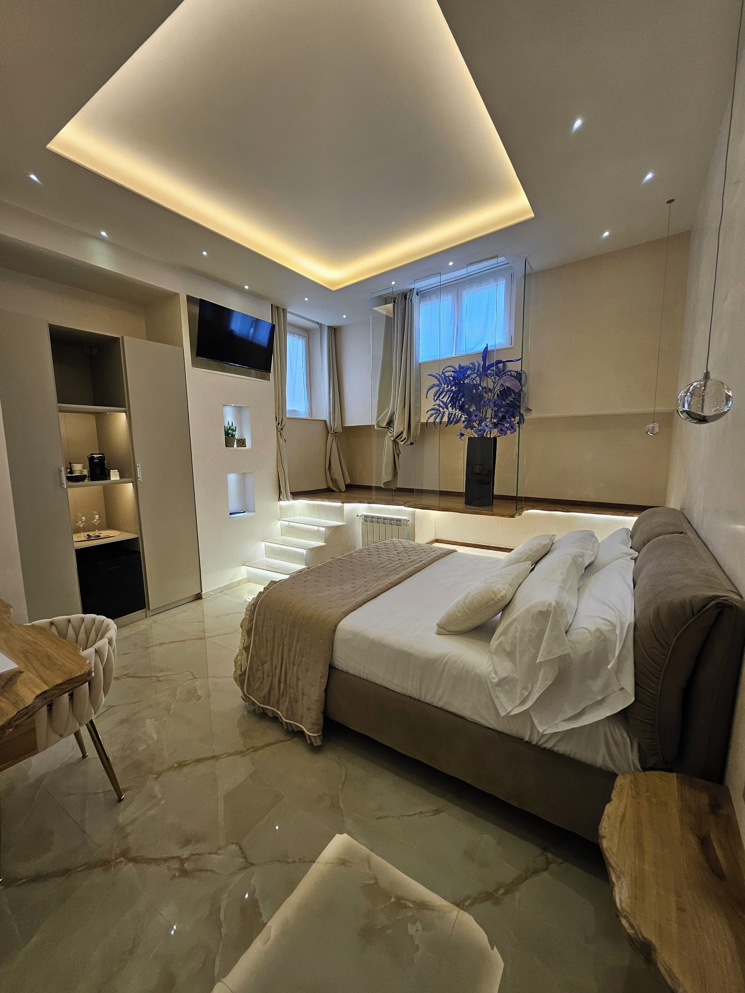 A modern bedroom with a large bed, a desk, and a TV.