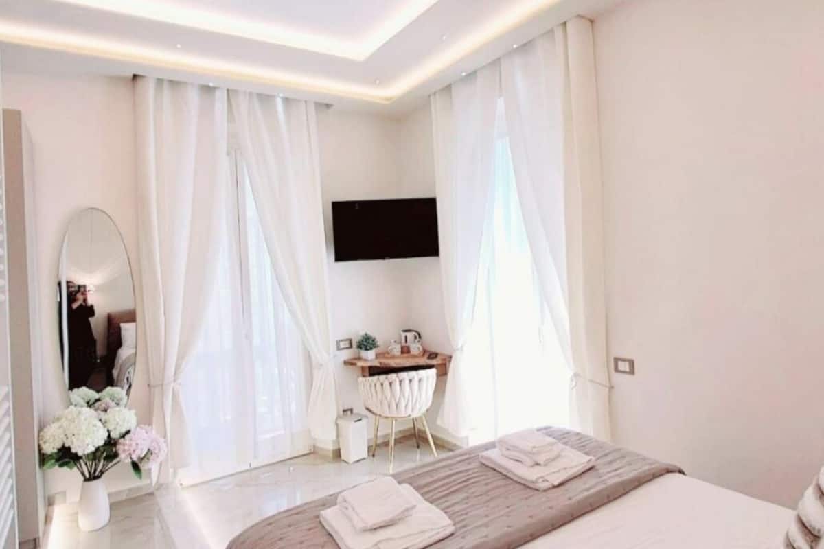 Una habitación de hotel moderna con una cama grande, un escritorio con televisor de pantalla plana y una tocador con espejo.