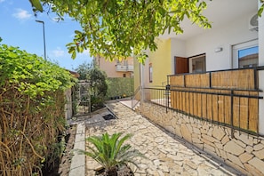 A stone-paved pathway leading to a building with a bamboo fence and a small plant.