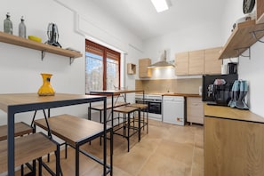 A compact kitchen with wooden cabinets, a built-in oven, and a coffee machine.