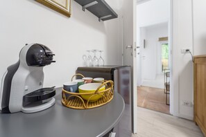 Eine Küchenzeile mit Kaffeemaschine, einer Geschirrkorb und einem Kühlschrank.