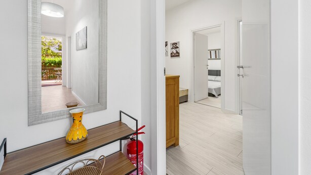 A hallway with a mirror, a wooden console, a fire extinguisher, and a door leading to a bedroom. - Apartment 'Nr 2' with Shared Pool and Garden (Pula)