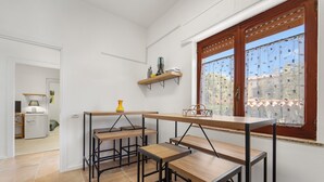A kitchen with wooden tables and chairs, a window with blinds, and a shelf with kitchen items. - Apartment Nr. 3, WLAN und Klimaanlage (Pula)