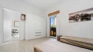 A bedroom with a bed, a wardrobe, a door leading to a balcony, and a cityscape painting. - Apartment Nr. 3, WLAN und Klimaanlage (Pula)