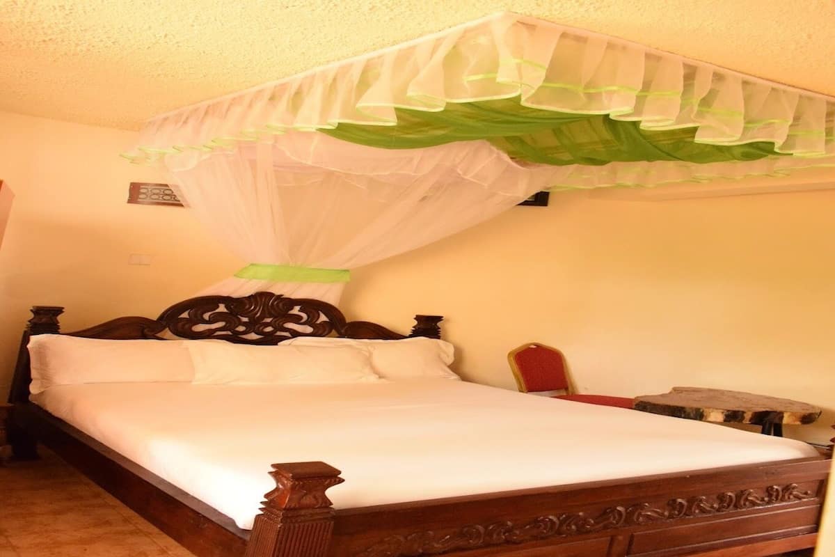 A bed with a canopy, a wooden headboard, and a nightstand with a lamp.