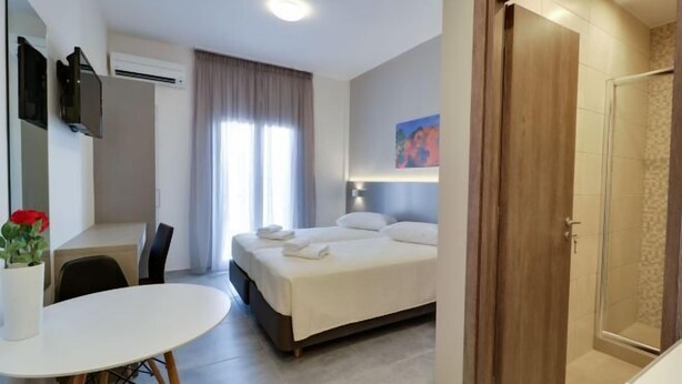 Ein Hotelzimmer mit einem Bett, einem Schreibtisch, einem Sessel, einem runden Tisch und einer Duschkabine.