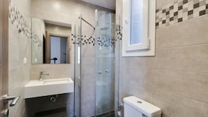 Ein modernes Badezimmer mit einer begehbaren Glasdusche, einem weißen Waschbecken und einer Toilette.