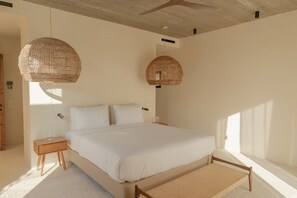 Un dormitorio con una cama grande, dos mesitas de noche y dos lámparas colgantes de mimbre.
