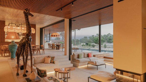 Un interior moderno con una escultura de jirafa, una piscina y un comedor con luz natural.