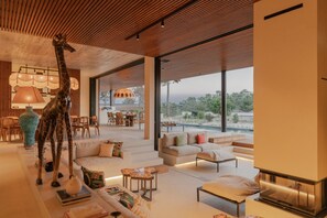 Un interior moderno con una escultura de jirafa, una piscina y un comedor con luz natural.