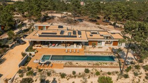Una casa moderna con piscina, paneles solares y un paisaje desértico.